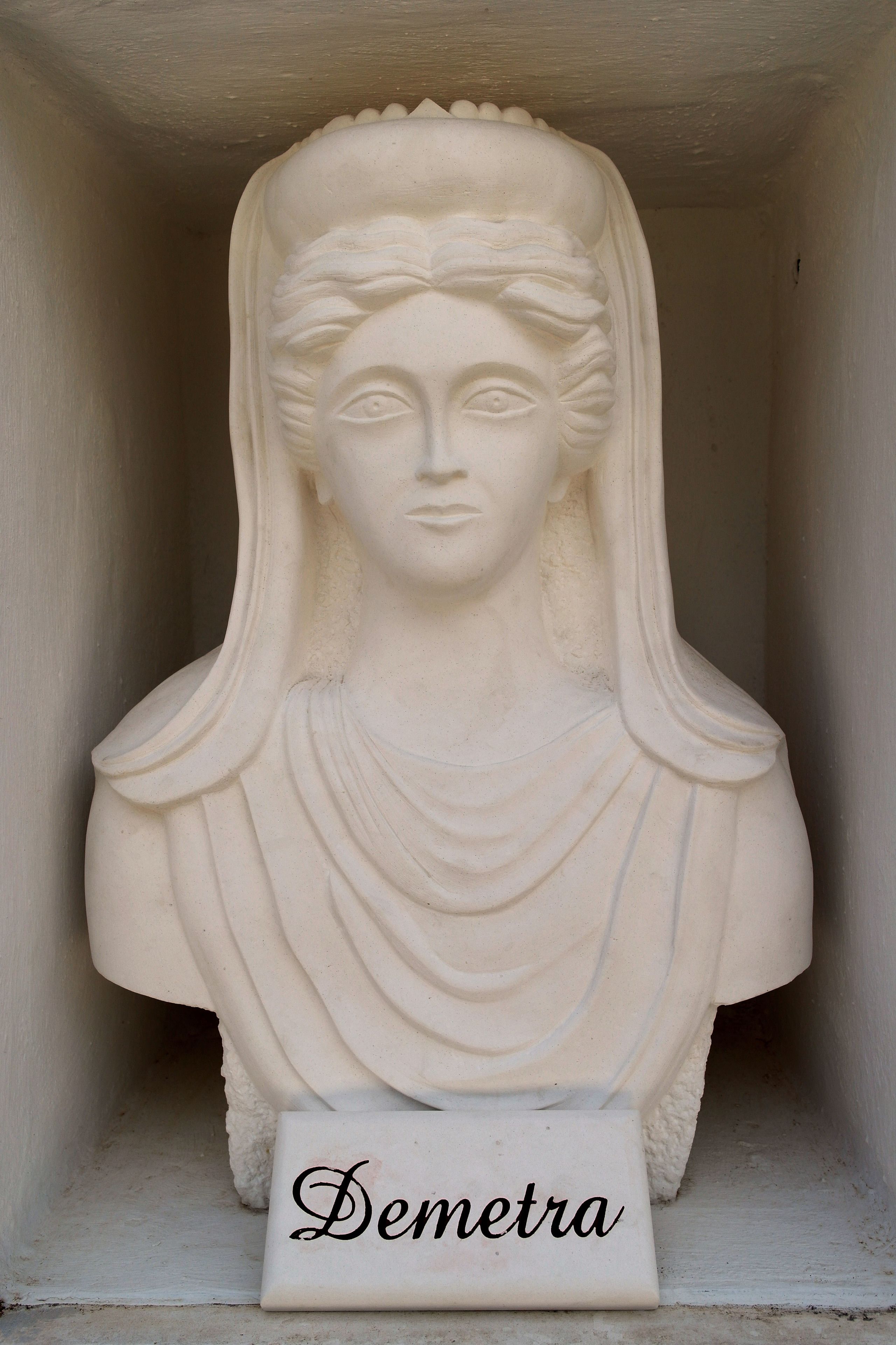 Un busto escultórico con la inscripción 'Demetra' en un nicho.