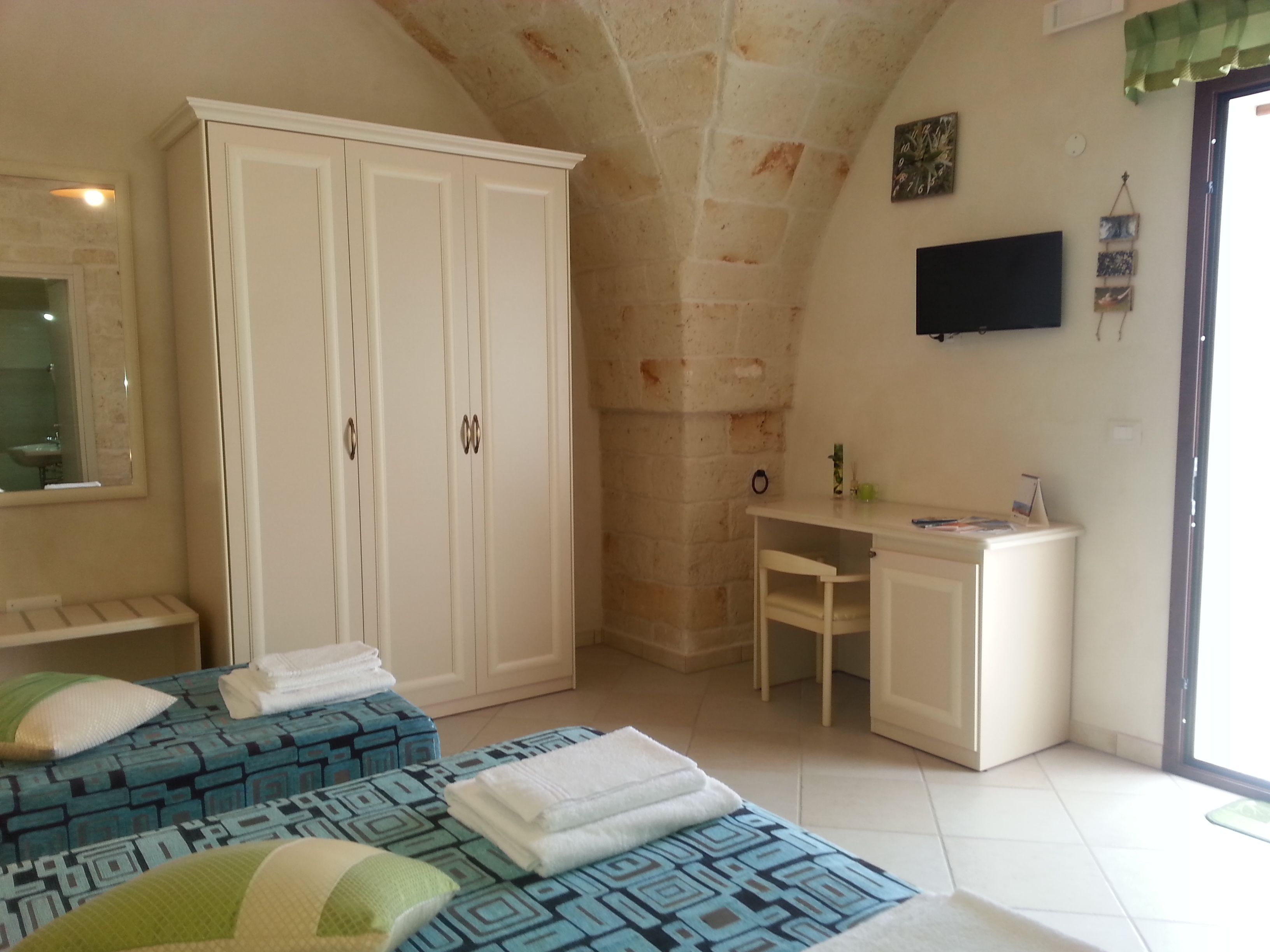 A bedroom with two beds, a wardrobe, a desk, and a chair.