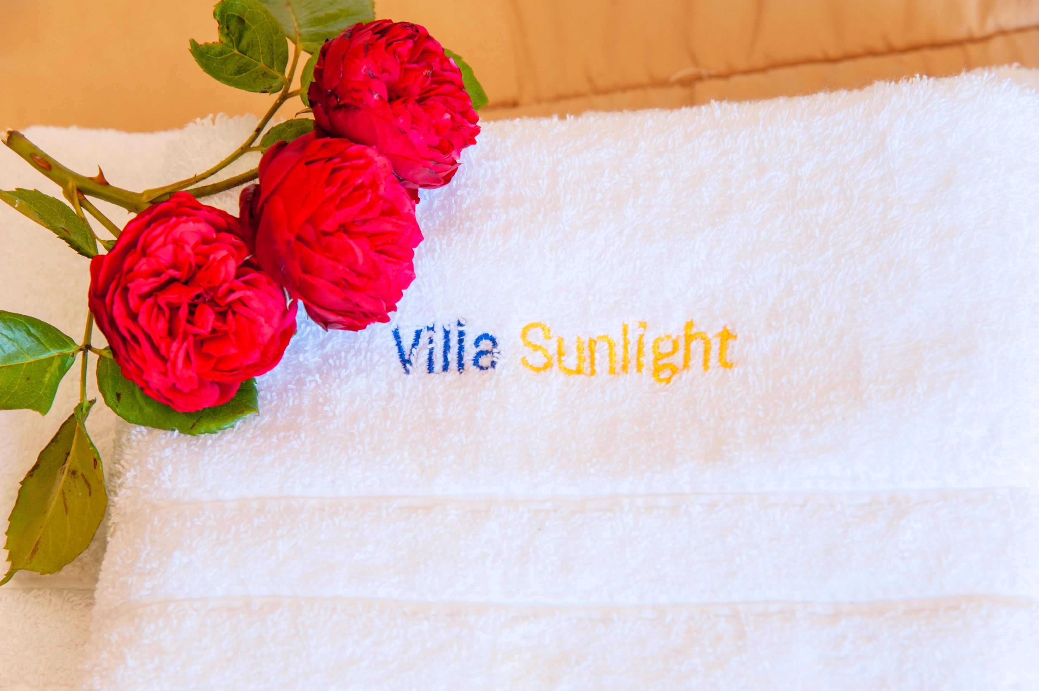 A white towel with the text "Ville Sunshine" and a branch of red roses.