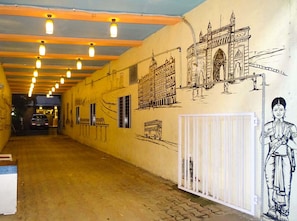 A corridor with a mural of the Taj Mahal and a person in traditional attire. - Sunshine Backpackers (Mumbai)