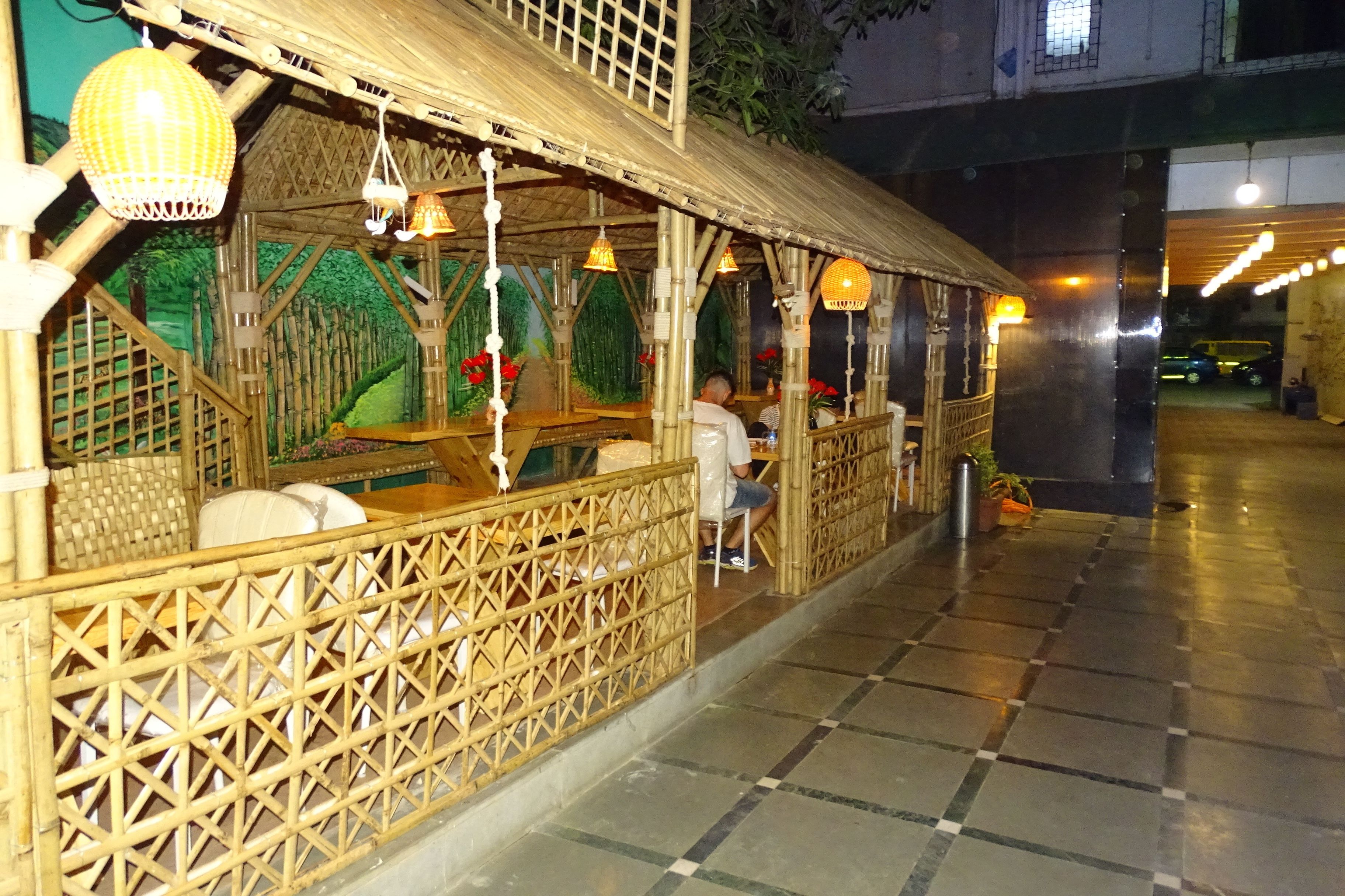 A restaurant with bamboo decor and hanging lights.