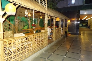 A restaurant with bamboo decor and hanging lights. - Sunshine Backpackers (Mumbai)