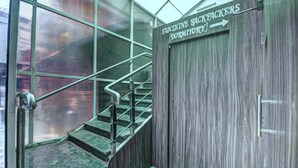 Una escalera con barandillas de metal que lleva a una puerta con la leyenda "Sunshine Backpackers Dormitory".