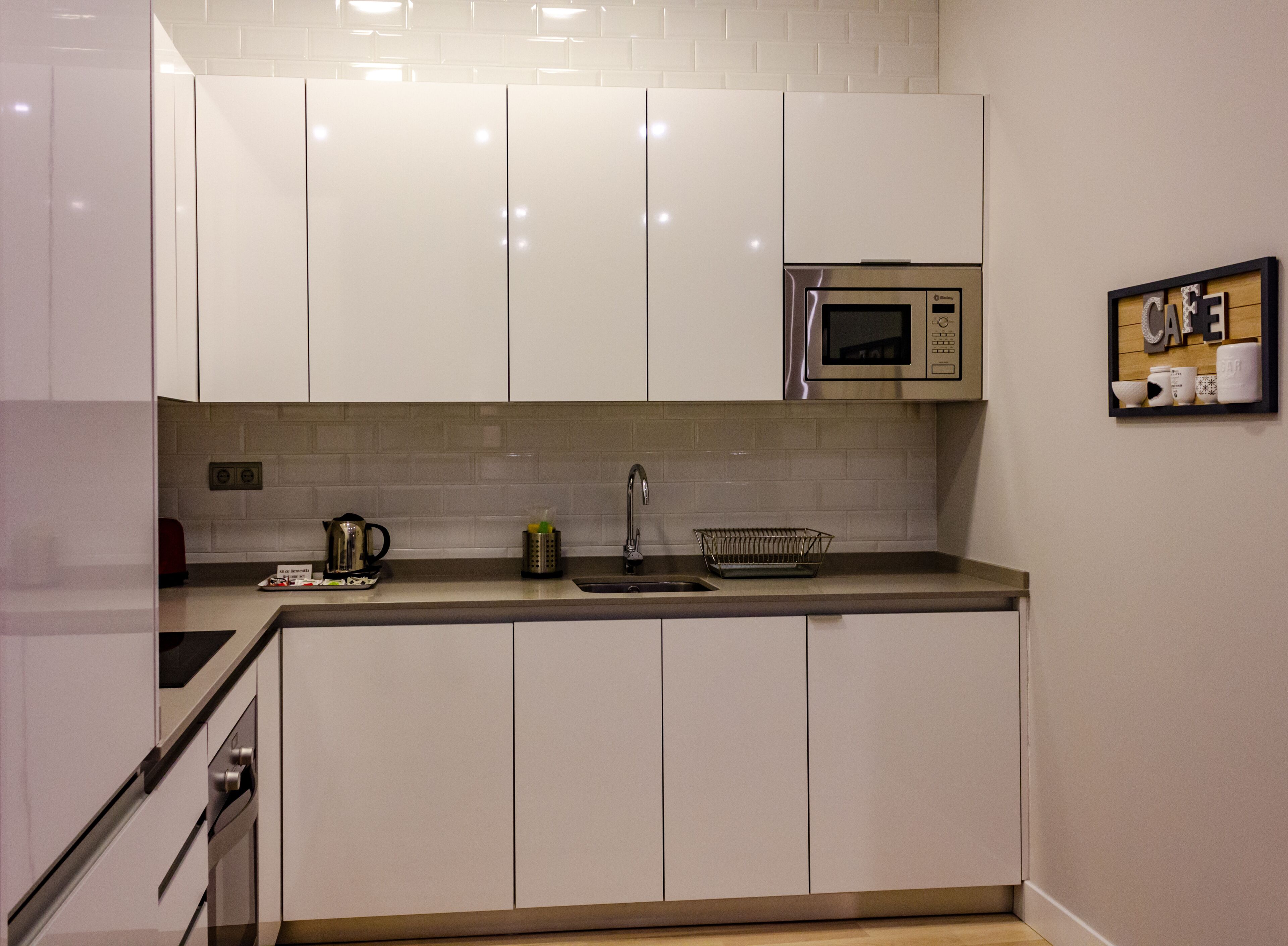 A modern kitchen with white cabinets, a stainless steel microwave, and a sink.
