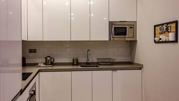 A modern kitchen with white cabinets, a stainless steel microwave, and a sink.