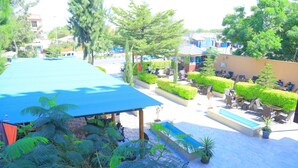 Una terraza en la azotea con techo azul, zonas de estar y una piscina.