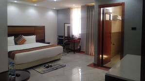 Habitación de hotel con cama, escritorio y baño a la vista a través de una puerta abierta.