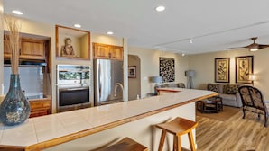 Una cocina moderna con una isla central, armarios de madera, electrodomésticos de acero inoxidable y una estatua de Buda.