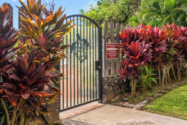 Una entrada con reja y un cartel que indica el horario de la piscina y la prohibición de entrada.