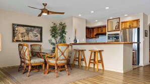Una cocina moderna con armarios de madera, un refrigerador de acero inoxidable y un comedor con sillas de mimbre.
