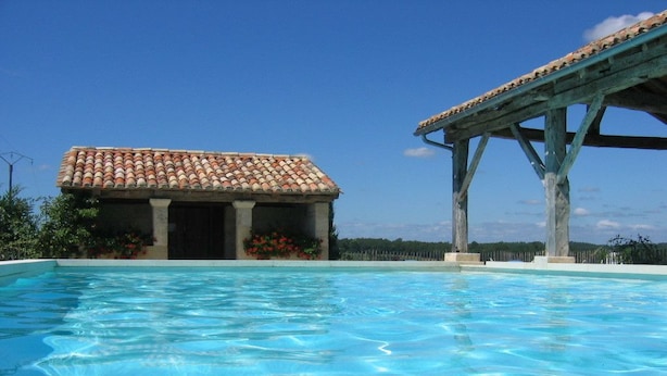 A swimming pool with a tiled roof structure and a small building with a tiled roof. - Domaine de la Mouthe (Saint-Remy)