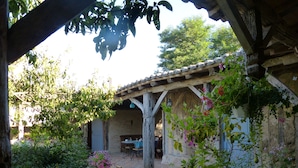 A rustic outdoor seating area with a table, chairs, and a hanging planter. - Domaine de la Mouthe (Saint-Remy)