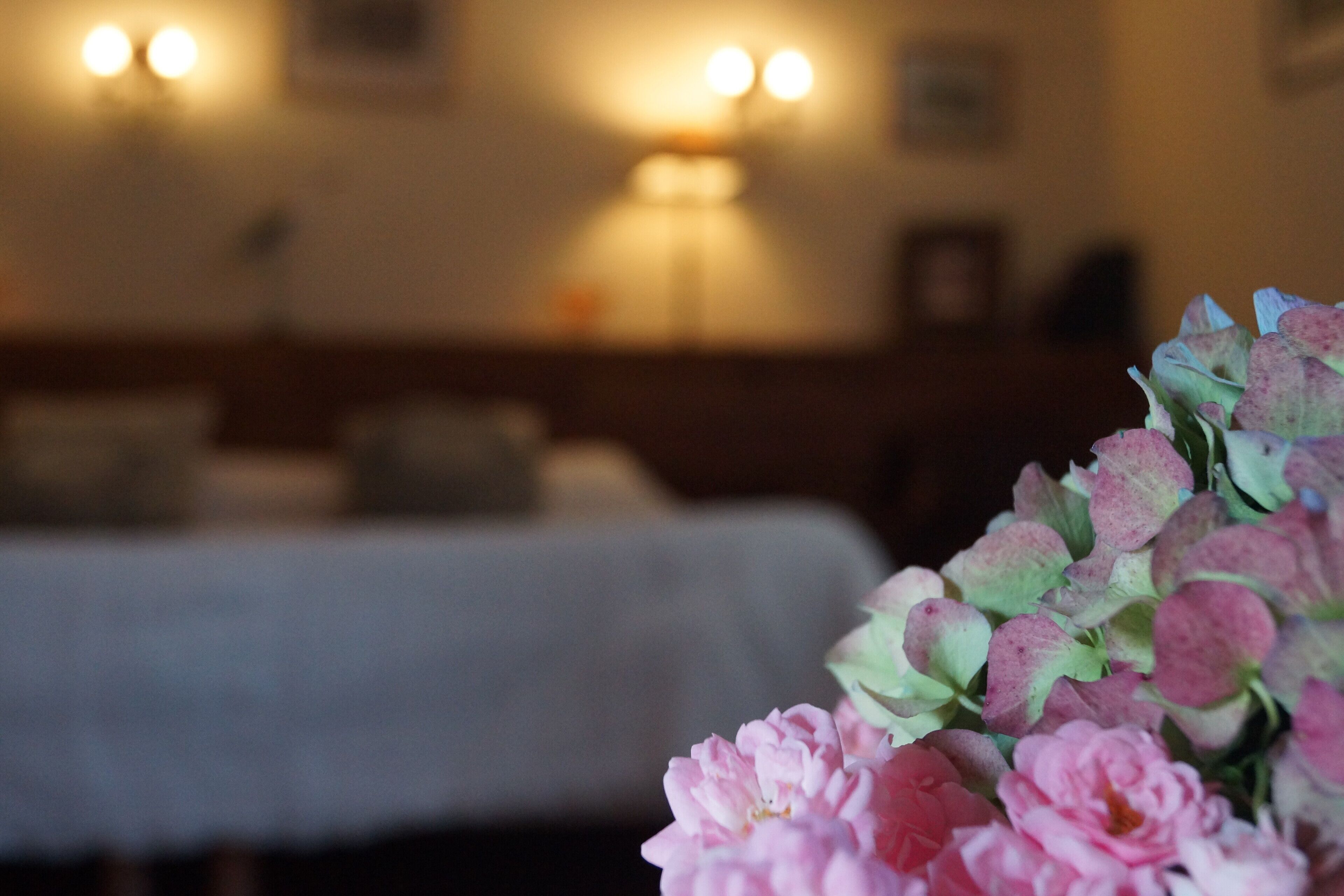 A room with a bed, a lamp, and a bouquet of flowers.