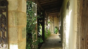 A stone pathway leading through a covered area with a rustic wooden ceiling and a sign that reads "PARKING". - Domaine de la Mouthe (Saint-Remy)