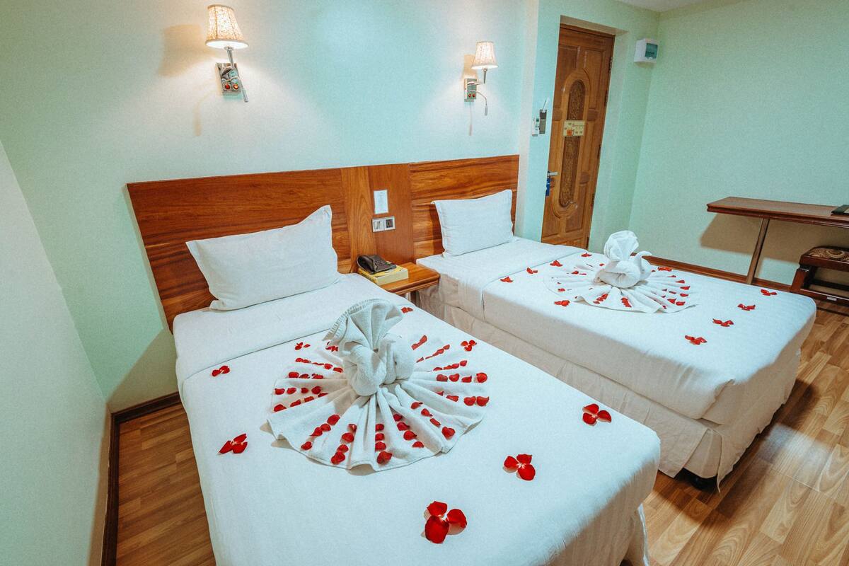 A hotel room with two beds, wooden headboards, and a small desk.