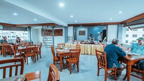 Un grand espace dédié à la salle à manger, avec des tables et des chaises en bois, un buffet et une vue sur les bâtiments environnants.