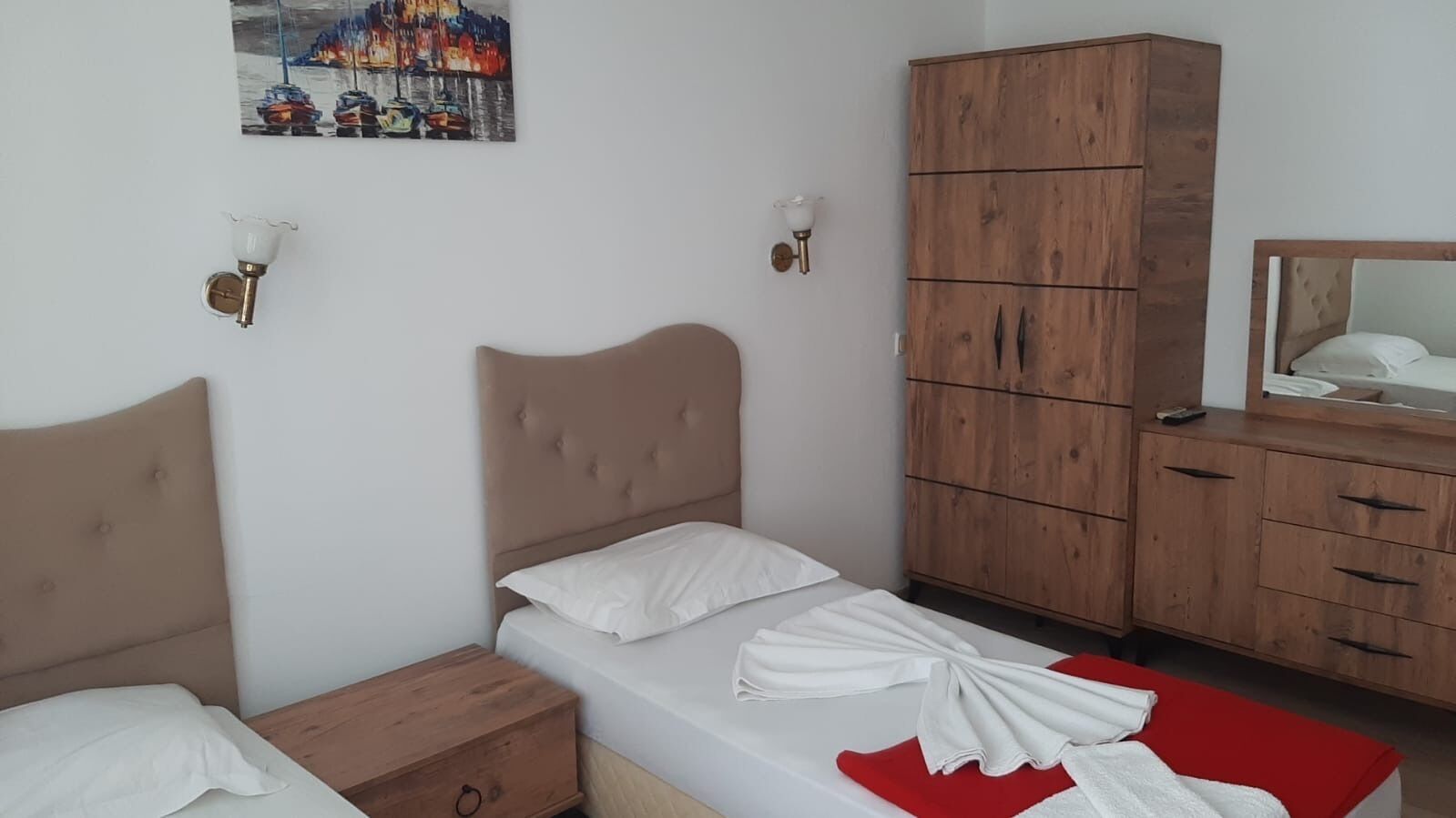A bedroom with two beds, wooden cabinets, and a painting on the wall.