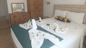 A hotel room with a bed, a wooden wardrobe, a mirror, and a painting on the wall. - Sevo Hotel (Ayvalik)