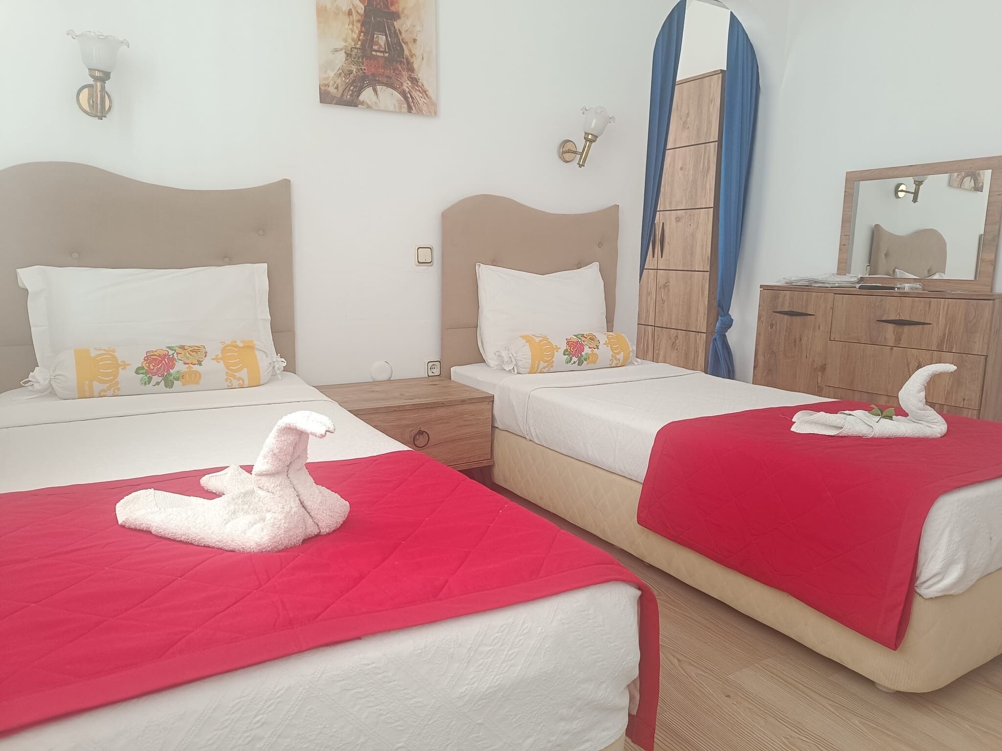 Two twin beds with red bedspreads, white pillows, and decorative swans.