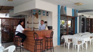 A bar area with a counter, stools, and a seating area with tables and chairs. - Sevo Hotel (Ayvalik)