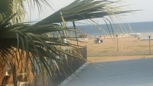 A view from a balcony overlooking a beach with palm trees and a clear sky. - Sevo Hotel (Ayvalik)