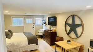 Une chambre à coucher de taille réduite, comprenant un lit, une table de chevet, une commode et un téléviseur fixé au mur.