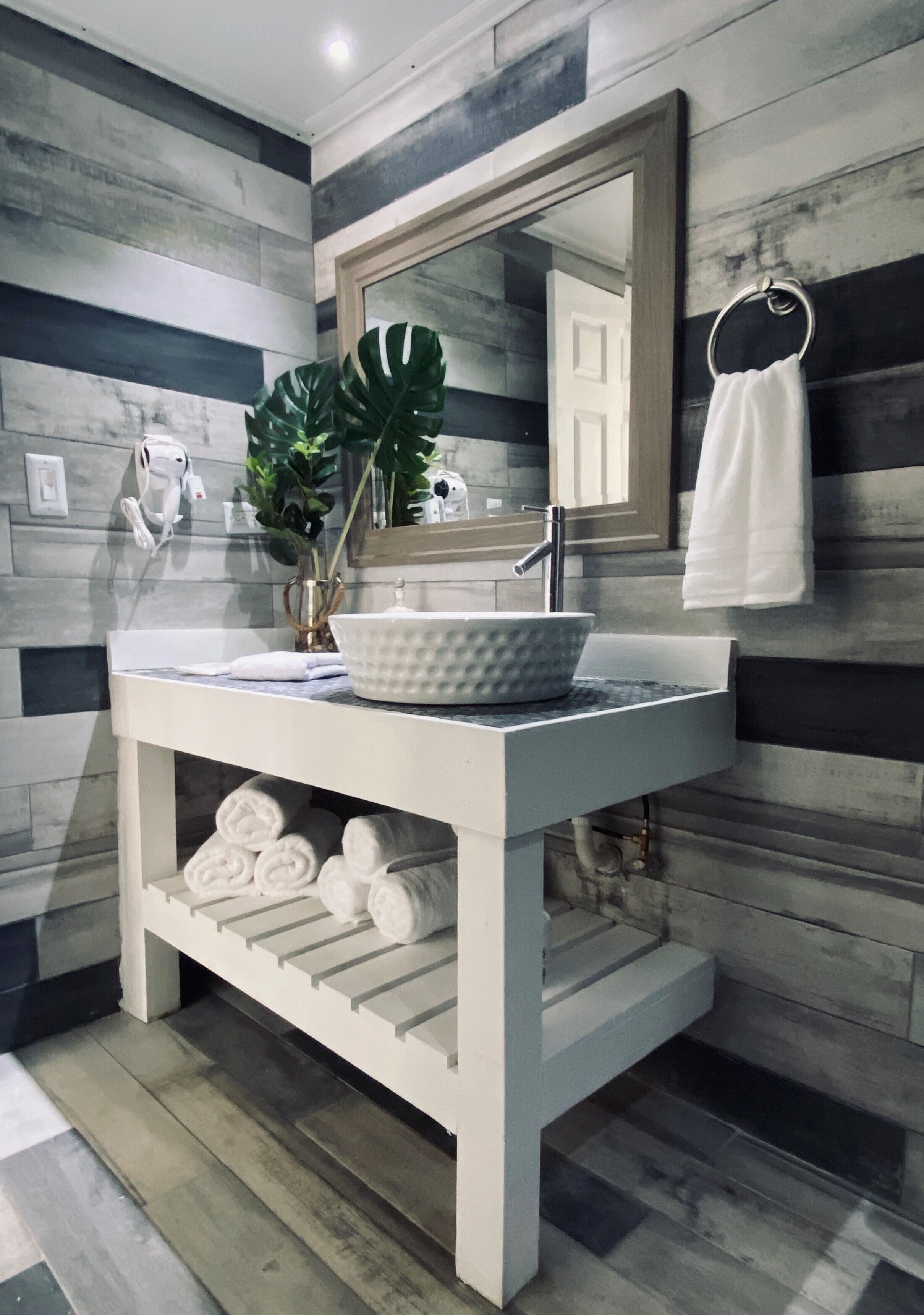 Une salle de bain moderne avec un meuble-lavabo blanc, un grand miroir et une plante en pot.