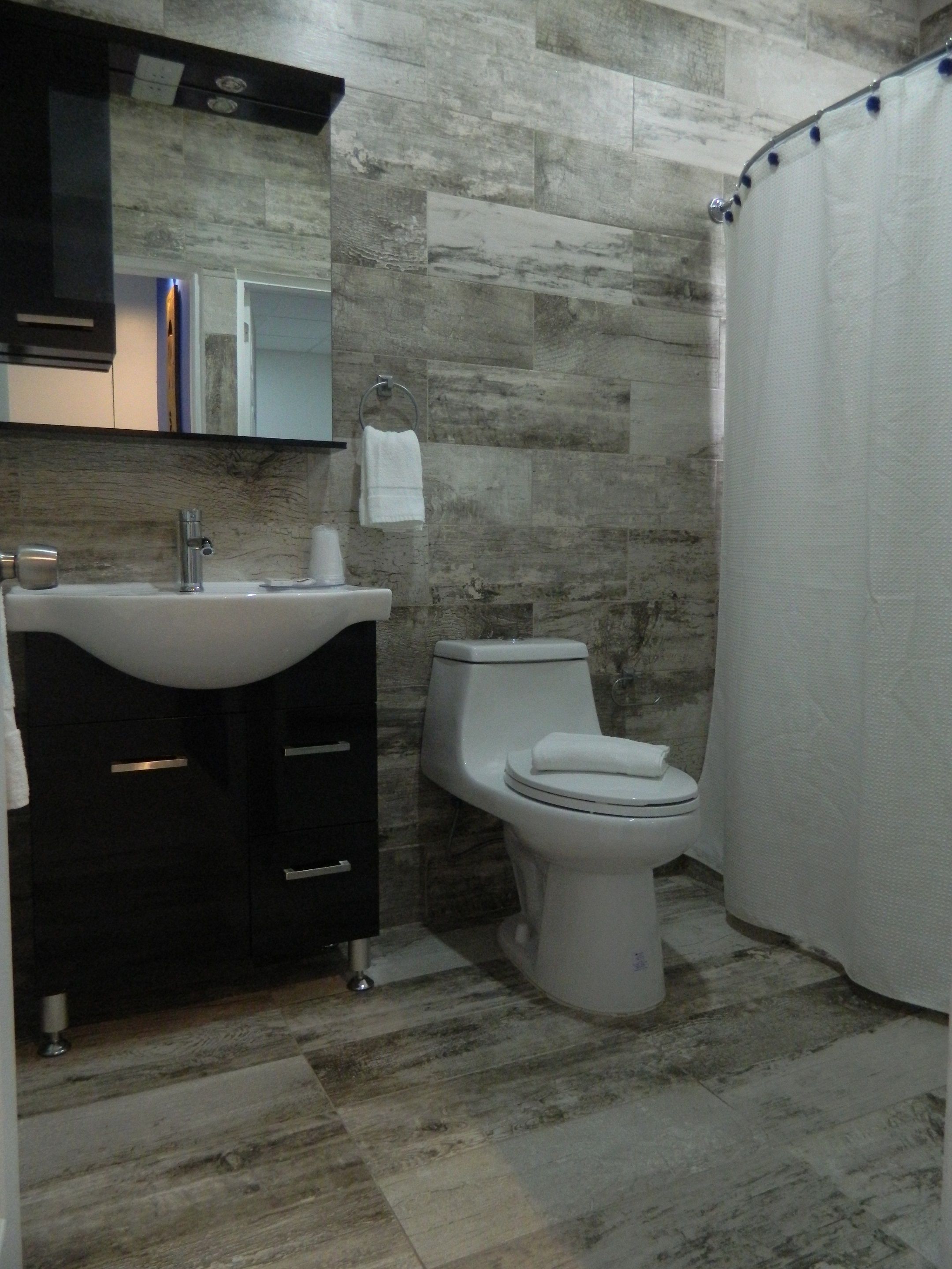 A bathroom with a sink, mirror, toilet, and shower curtain.