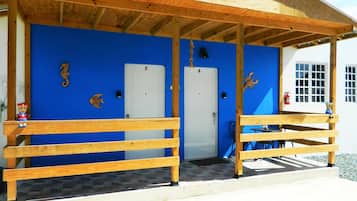A building with a blue exterior, wooden benches, and numbered doors.