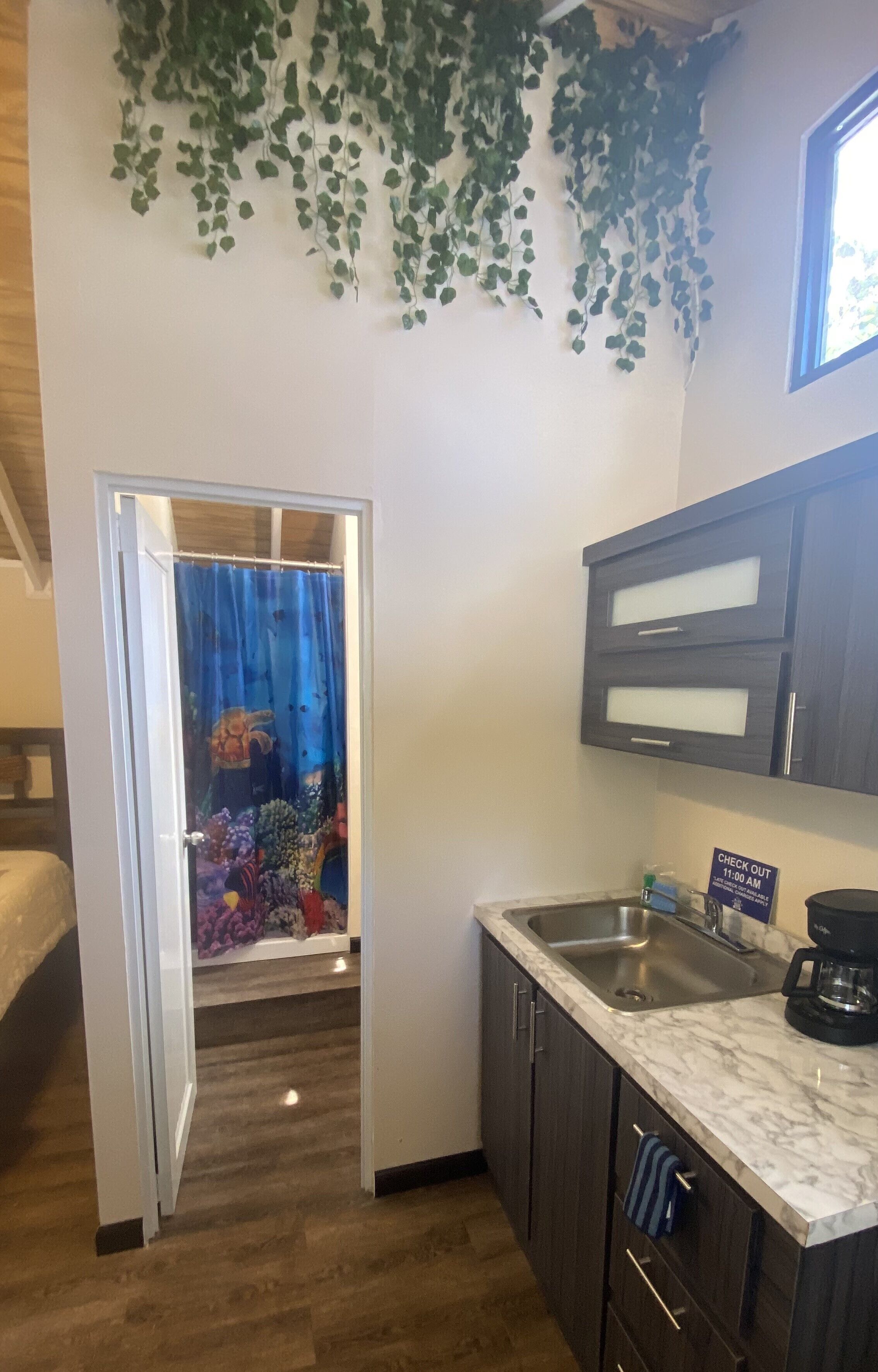 A compact kitchen with dark cabinets, a marble countertop, a sink, and a coffee maker.