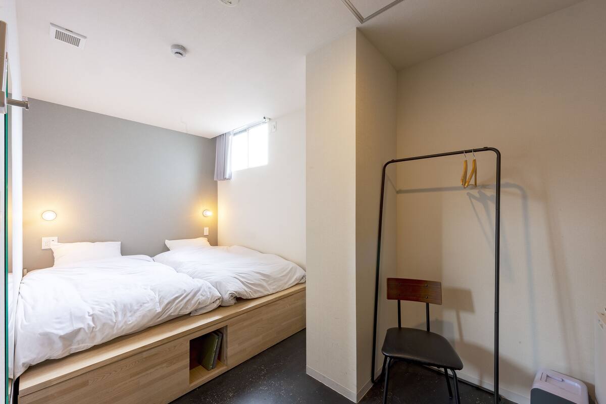 Une chambre à coucher moderne avec un lit, des tables de chevet, un banc et une fenêtre.