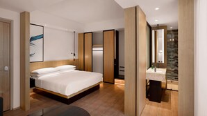 Een moderne hotelkamer met een groot bed, een aparte badkamer en een klein zithoekje.