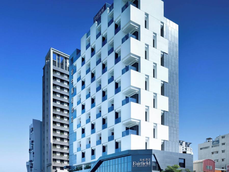 A modern high-rise hotel with a grid of balconies, a clear sky, and a visible Fairfield by Marriott sign.