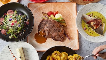 A variety of dishes including a steak, pasta, and a salad, suggesting a diverse meal selection.