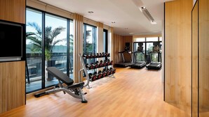 Een moderne sportschool met trainingsapparatuur, grote ramen en een loopband.