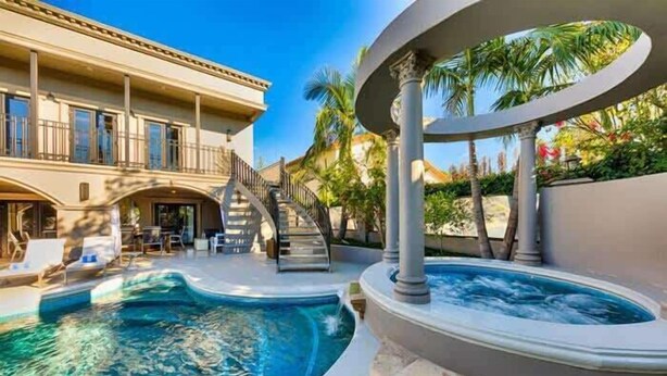 Une piscine avec un jacuzzi, un escalier et un bâtiment doté de balcons.