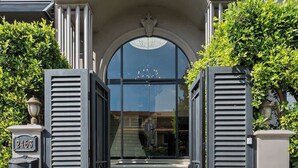 Une entrée d’immeuble avec une grande porte en arc de cercle, un lustre et des marches menant à l’entrée.
