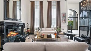 Un salon avec une cheminée, un canapé, une table basse et un lustre.