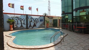 Una piscina al aire libre, sillones reclinables de piscina