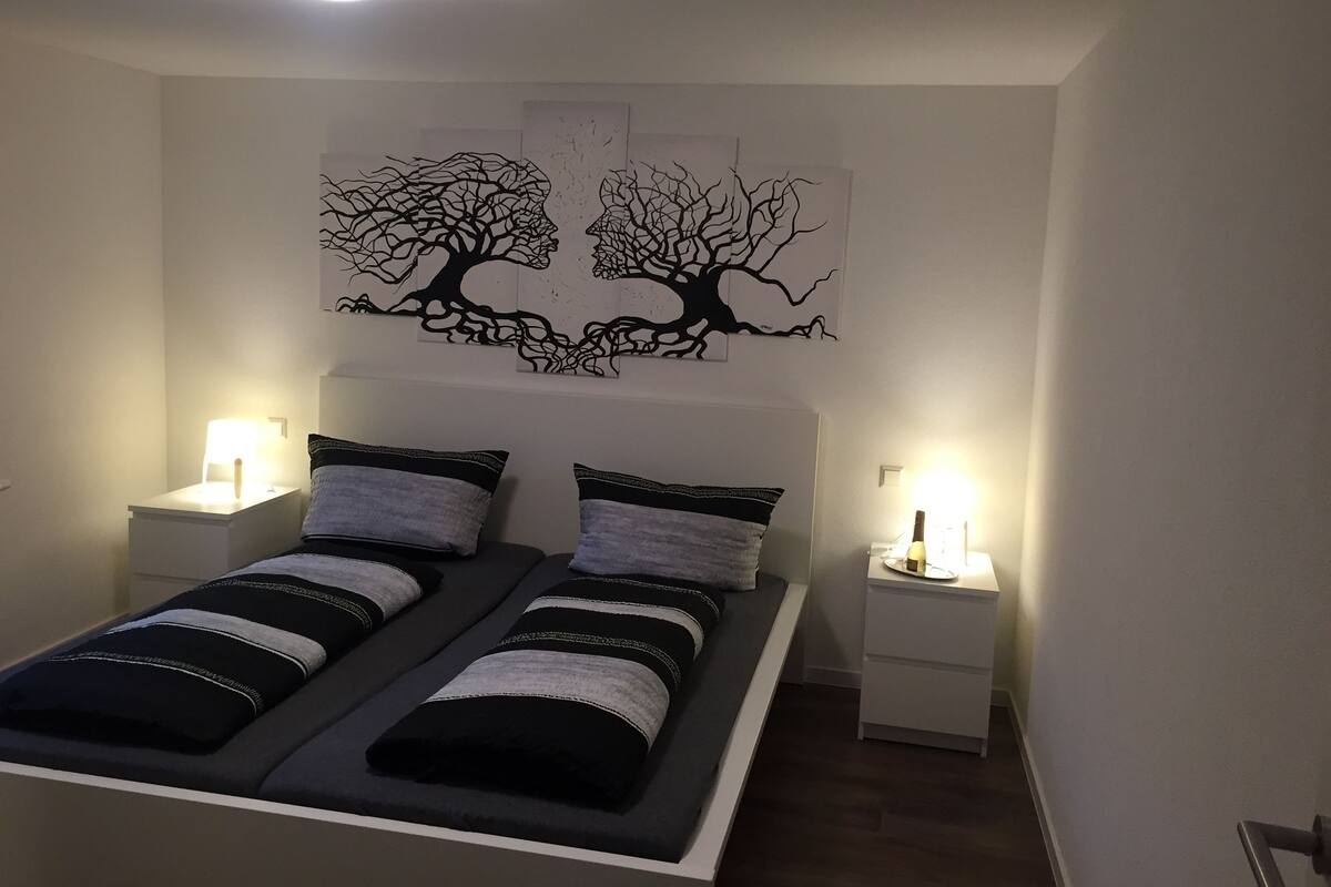 Un dormitorio con una cama, dos mesitas de noche y decoración en la pared.