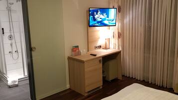 A bathroom with a shower, toilet, and a TV mounted on the wall.