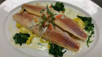 Ein Teller mit Fischfilet, Gemüse und cremiger Soße.