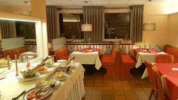 A dining area with multiple tables and booths, each set with plates, bowls, and cutlery.