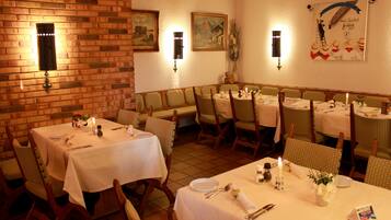 A restaurant with brick walls, white tablecloths, and wicker chairs.