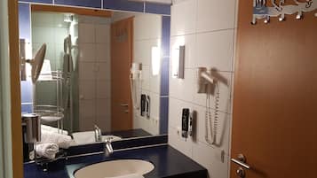 A bathroom with a sink, mirror, towel rack, and two hair dryers mounted on the wall.
