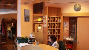 A hotel reception area with a marble counter, wooden shelves with wine glasses, and a clock on the wall. - Hotel Fröhlich (Kaiserslautern)