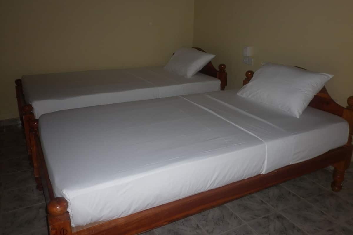 A double bed with wooden headboard and footboard, two pillows, and a bedside table with a lamp.