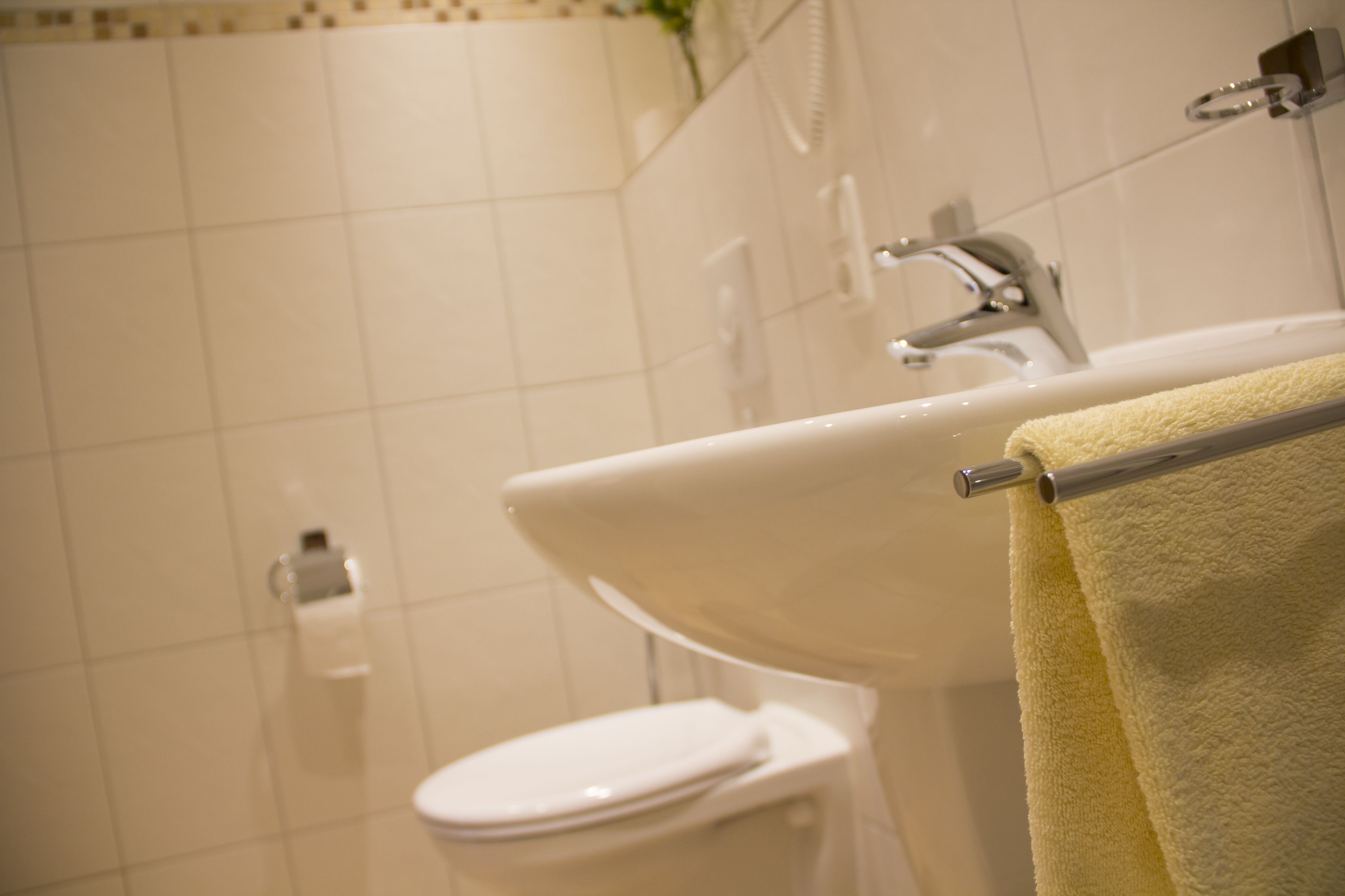 Un baño con un lavamanos blanco, un inodoro y un perchero con una toalla amarilla.