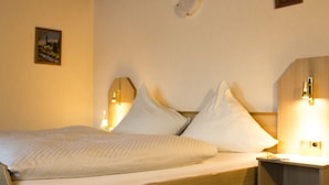 A neatly made bed with white linens, a wooden headboard, and two bedside lamps. - Zur Neroburg (Neroth)