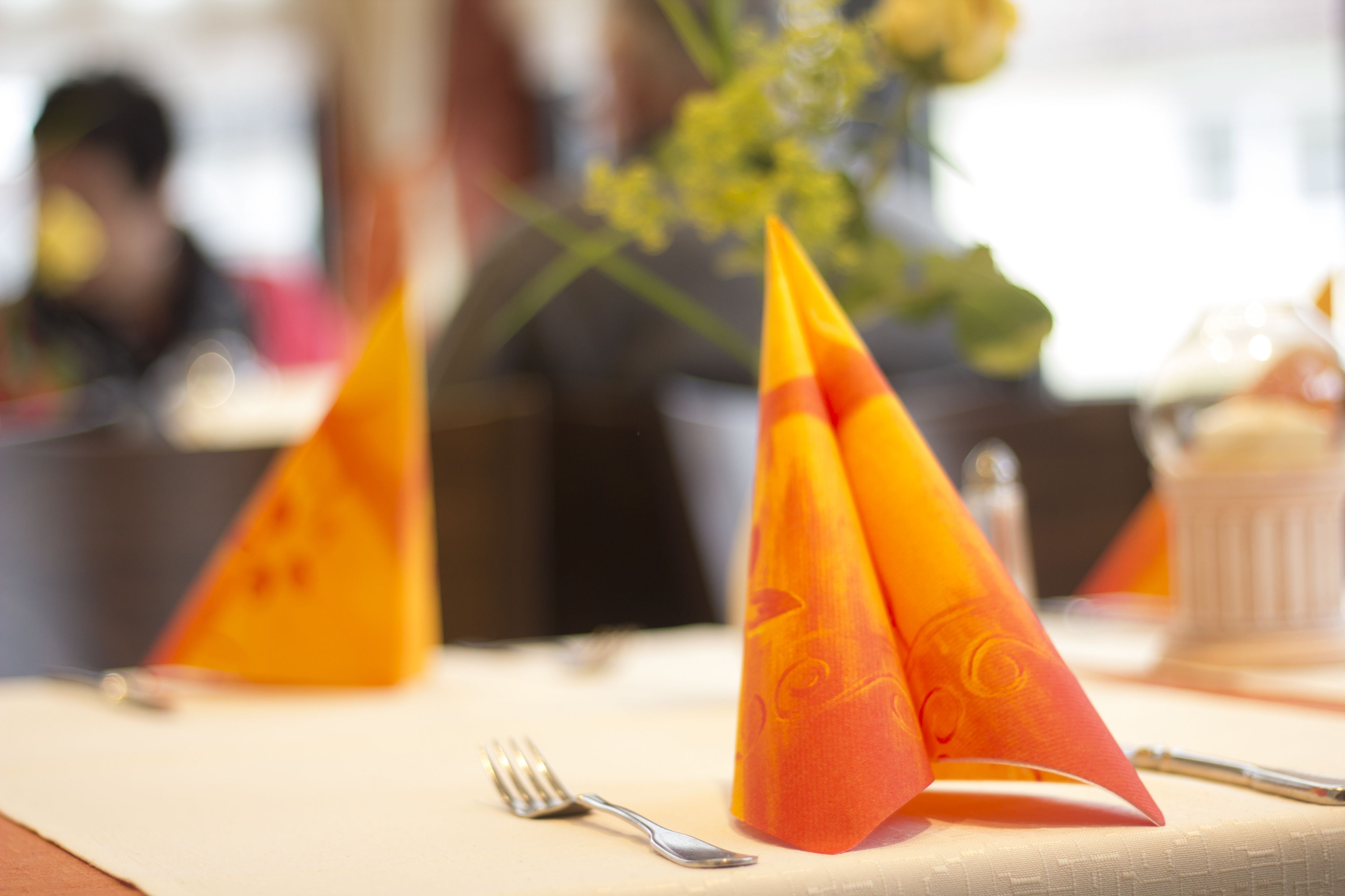 A table with a folded napkin, a fork, and a glass.